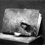 Vue de l'Exposition d’œuvres d'art mutilées ou provenant des régions dévastées par l'ennemi au Petit Palais, 1916. Volume transpercé par un obus, provenant de la bibliothèque de Verdun. Collection Agence Meurice. © Bnf, estampes et photographie.