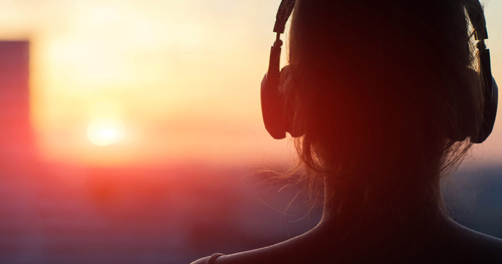 Femme écoutant de la musique face au soleil