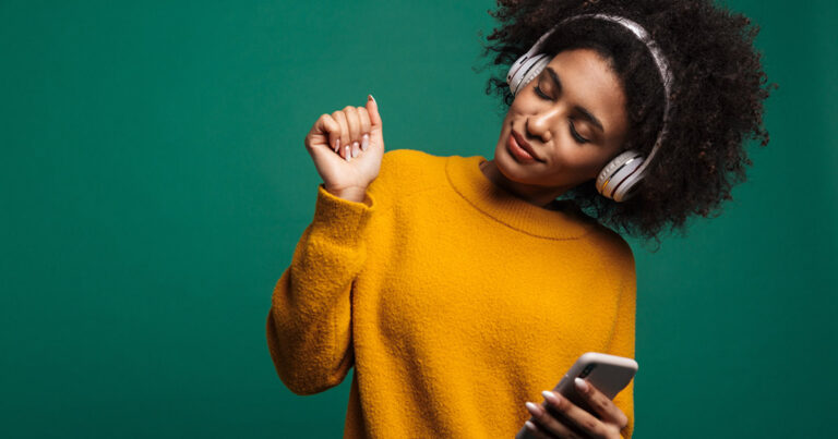 Curly woman listening music with headphones